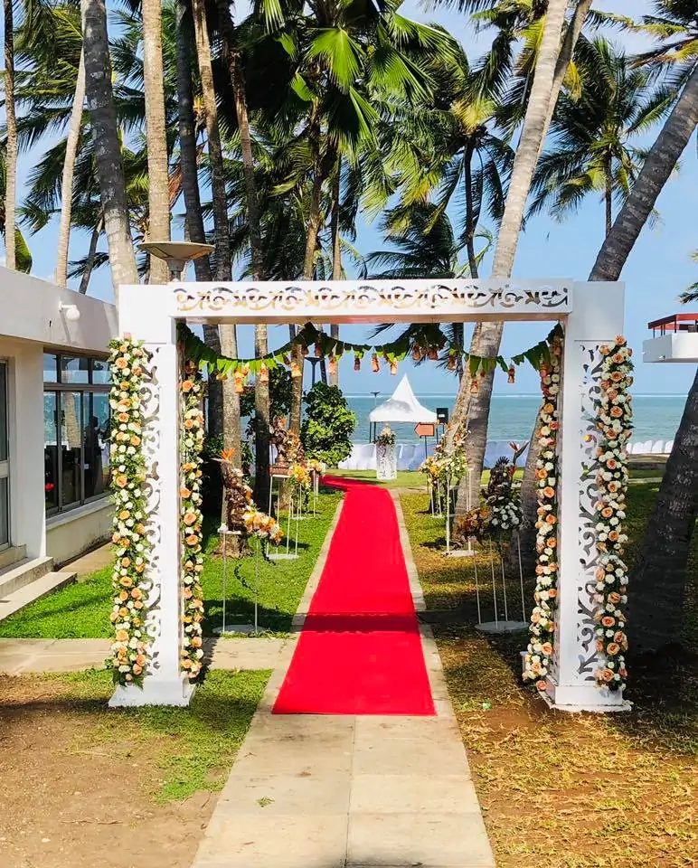Floral wedding arch and red carpet leading to the beach at Kenya Bay Beach Hotel